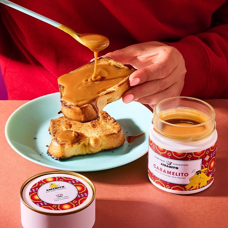 Confiture Parisienne Caramelito Dulce De Leche - model shown putting product on toast near open product jar