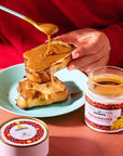 Confiture Parisienne Caramelito Dulce De Leche - model shown putting product on toast near open product jar