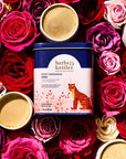 Herbs & Kettles Rose Cardamom Chai - product packaging shown on top of roses and cups of tea