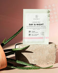 Lifestyle shot of SMARTMED Day & Night Hydrocolloid Patch Duo (60 patches) on cement brick with aloe vera plant on its side in the foreground