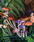 Lifestyle shot of Moth & Myth Ferns & Friends Psychedelic Mini Set (7 pcs) with green foliage and ferns in the background