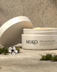 Moko Manuka Paw Balm - product shown with lid off next to flowers