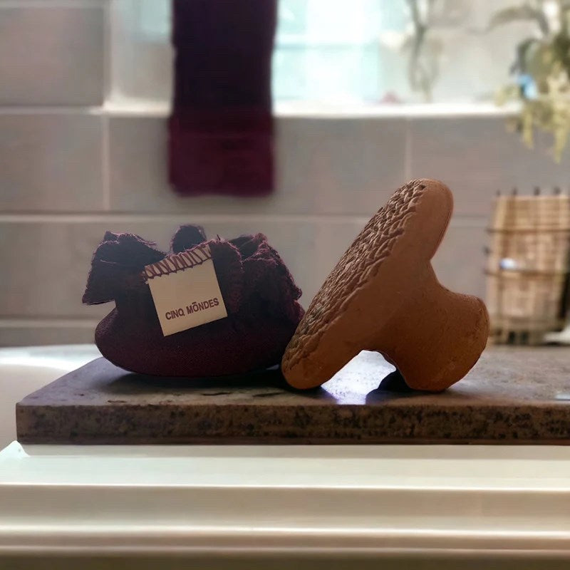 Cinq Mondes Moroccan Clay Pumice Stone Foot Exfoliant - product shown next to included bag in bathroom