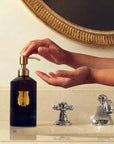 Lifestyle shot of model using Trudon Medie Hand Soap (350 ml) at bathroom sink