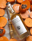 Flamingo Estate Organics Winter Harvest Persimmon Vinegar - product shown next to to sliced persimmons