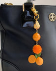 Lenora Dame Freshly Squeezed Orange Bag Charm - product shown attached to purse