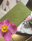 The Quiet Botanist The Matcha Rose Chocolate Bar - product shown next to flower and packaging