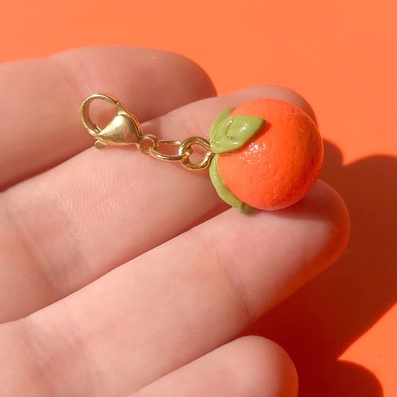 Bold Blossom Shop Tangerine Bag Charm - model shown holding product