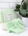 VOESH New York Moisturizing Heel Socks - Green - products shown next to packaging and potted plant