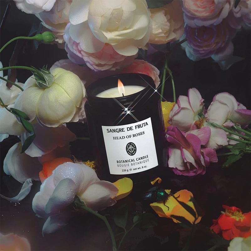 Sangre de Fruta Head of Roses Botanical Candle - lit product shown with roses and flowers