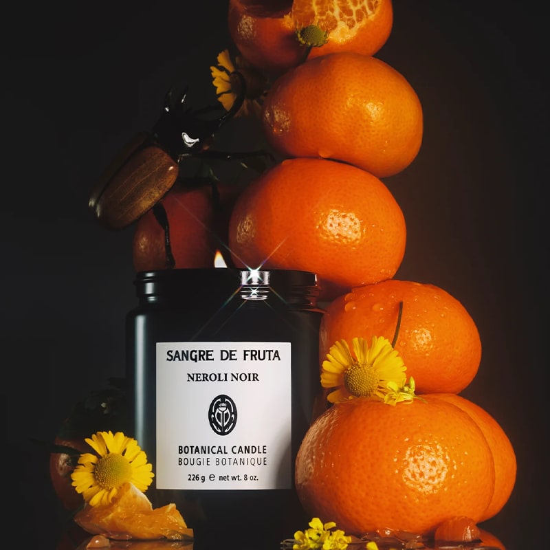 Sangre de Fruta Neroli Noir Botanical Candle - product shown with oranges and flowers with beetle