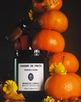 Sangre de Fruta Neroli Noir Botanical Candle - product shown with oranges and flowers with beetle