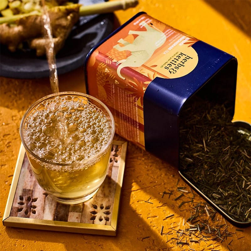 Herbs & Kettles Ginger Lemongrass Tea - product packaging shown opened and contents spilling out next to glass of tea