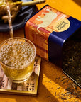 Herbs & Kettles Ginger Lemongrass Tea - product packaging shown opened and contents spilling out next to glass of tea