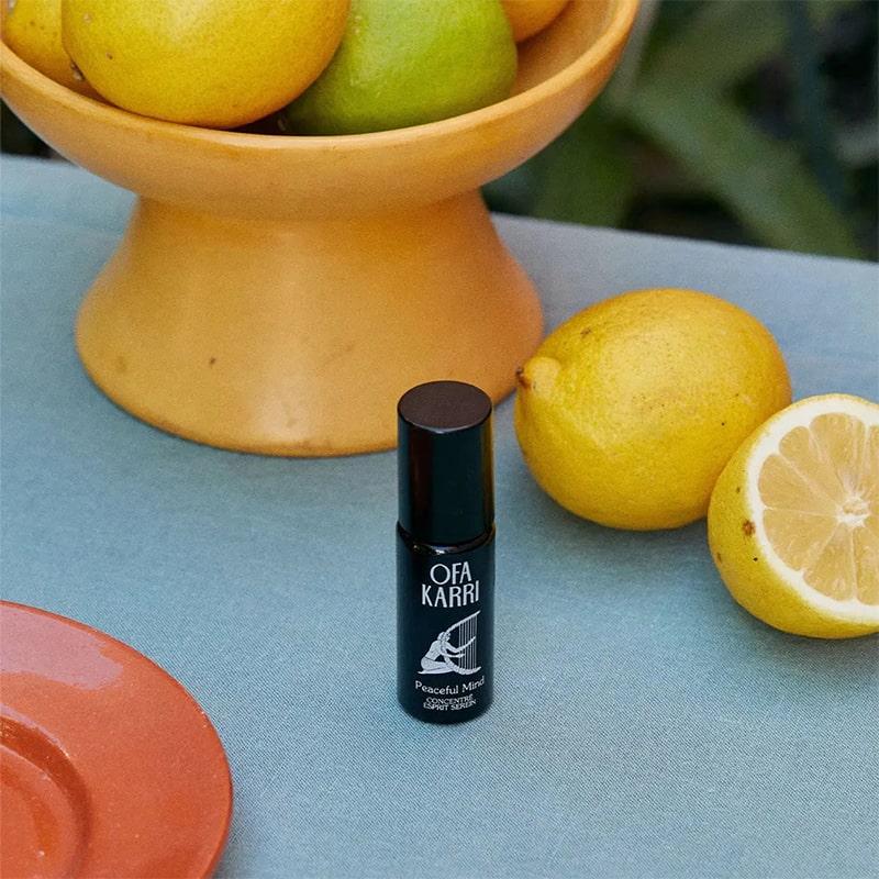 Lifestyle shot of Ofa Karri Peaceful Mind Roll-On (10 ml) with lemons in the background