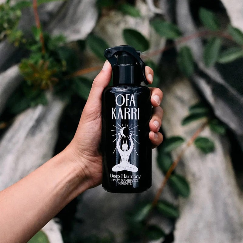 Model holding Ofa Karri Deep Harmony Home Spray (200 ml) with leaves in the background