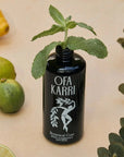 Lifestyle shot of Ofa Karri Botanical Cure Home Spray (200 ml) with top off and mint placed in bottle