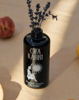 Lifestyle shot of Ofa Karri Sunshine Therapy Home Spray (200 ml) with top off and lavender placed in bottle