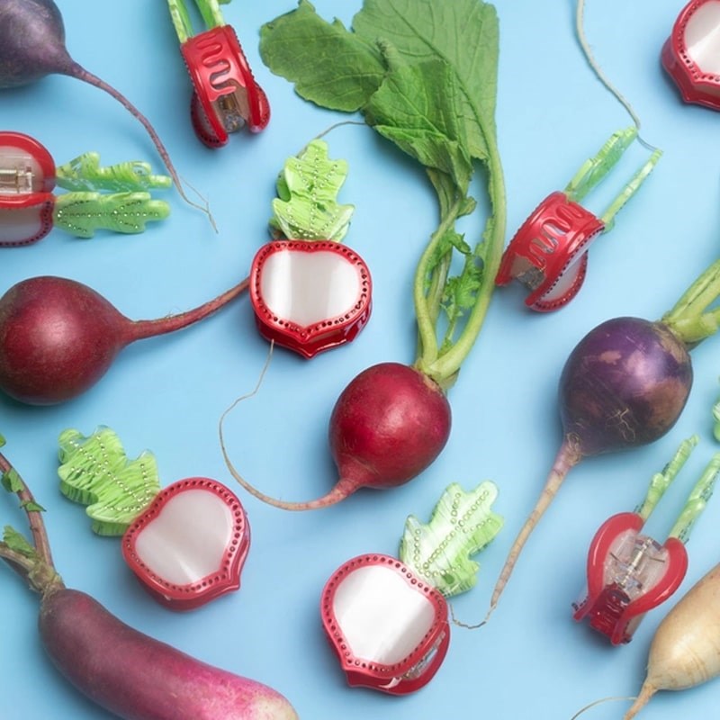 Lifestyle shot of Winona Irene Fancy Rhinestone Radish Slice Claw (multiple) scattered among radishes (clips sold separately)