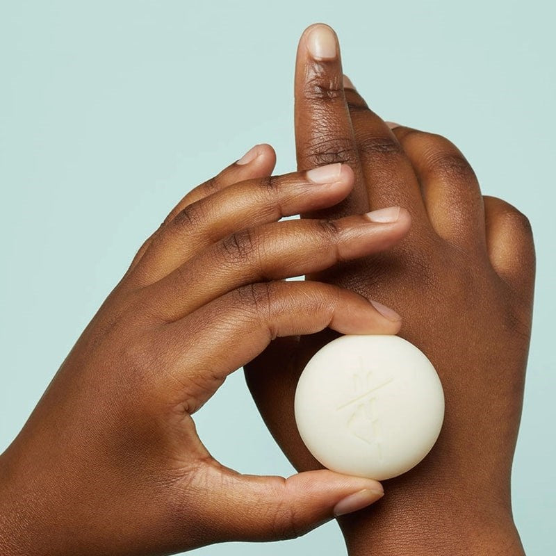 Close up shot of model using Kate McLeod mini moisturizing stone on back of hand