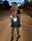 Firefly Reflectors Reflective Pom Pom - Rose shown on girl's backpack at night reflecting