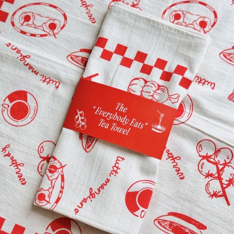 Mel Andrel Everybody Eats Tea Towel - product folded and packaging band shown