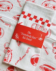 Mel Andrel Everybody Eats Tea Towel - product folded and packaging band shown