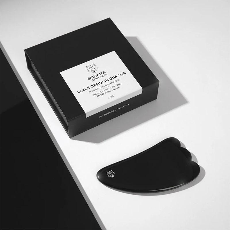 Snow Fox Skincare Black Obsidian Hot Stone Gua Sha - product shown next to packaging on table