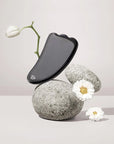 Snow Fox Skincare Black Obsidian Hot Stone Gua Sha - product shown on rocks with flowers