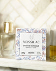 Nossilac Authentic Marseille Soap Cube - product packaging shown on shelf with bottles