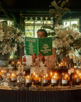 Flamingo Estate Organics The Guide to Becoming Alive - model shown holding product near lit candles and flowers